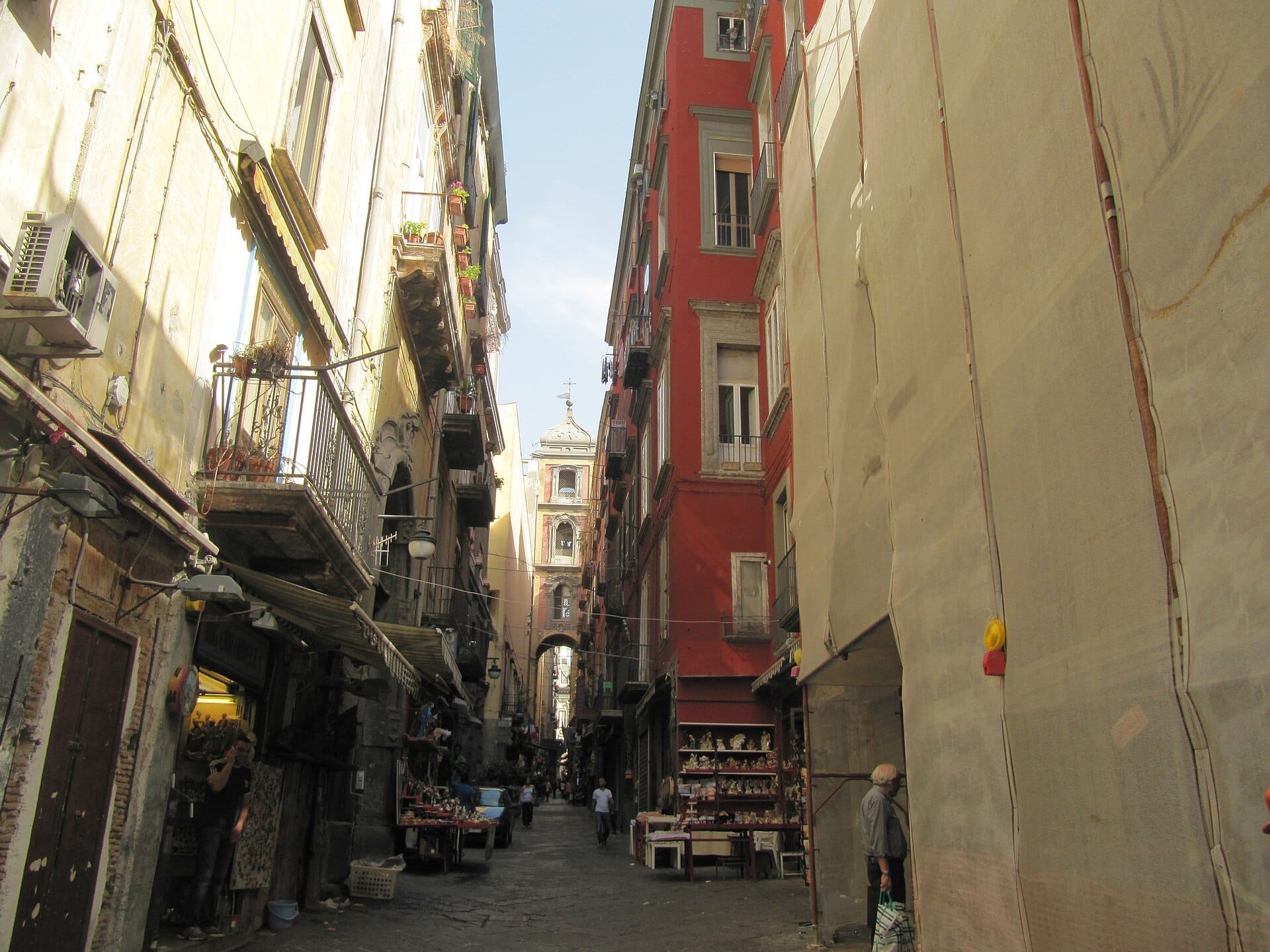 Stradina stretta fiancheggiata da edifici storici e botteghe artigiane con statuine di presepe nella Via San Gregorio Armeno di Napoli.