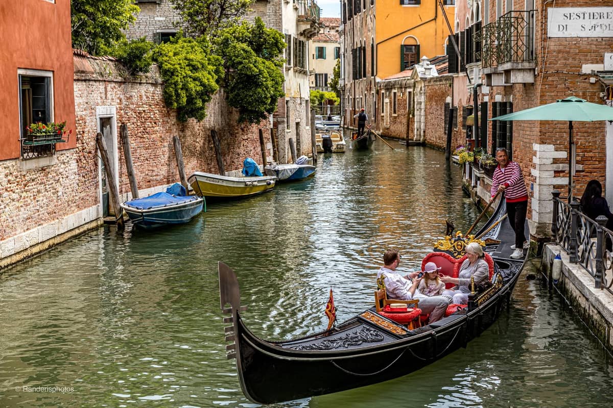 Ein malerischer Kanal in San Polo, Venedig, mit einer Gondel, vertäuten Booten, rustikalen Gebäuden und einem Straßenschild für das Sestiere di S. Polo.