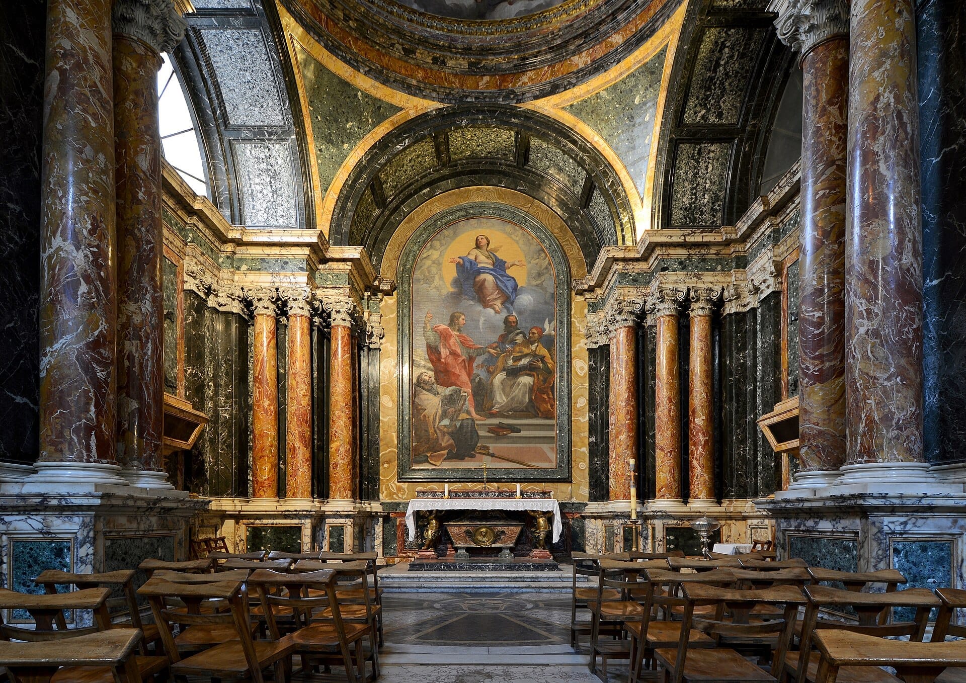 Central nave of Santa Maria del Popolo with marble columns, wooden chairs, and a large Renaissance painting illuminated by natural light.