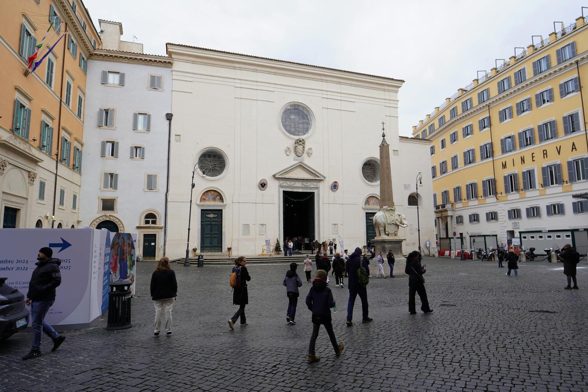 Wide view of the Basilica di Santa Maria sopra Minerva with Bernini's elephant obelisk and people in the piazza in front of the church.