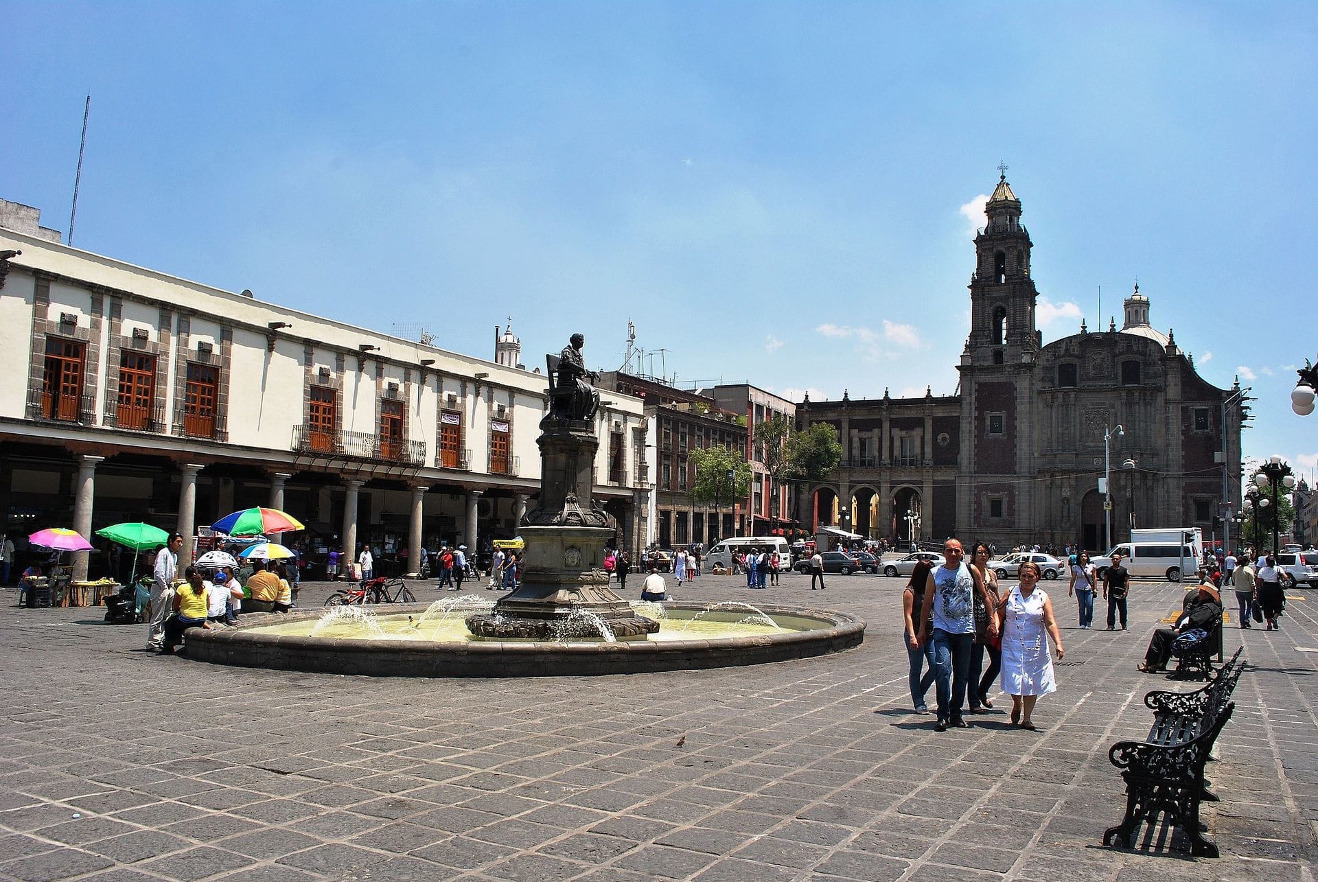 La Plaza de Santo Domingo presenta una fontana centrale, edifici coloniali storici, una chiesa barocca e persone che godono della vivace piazza pubblica.