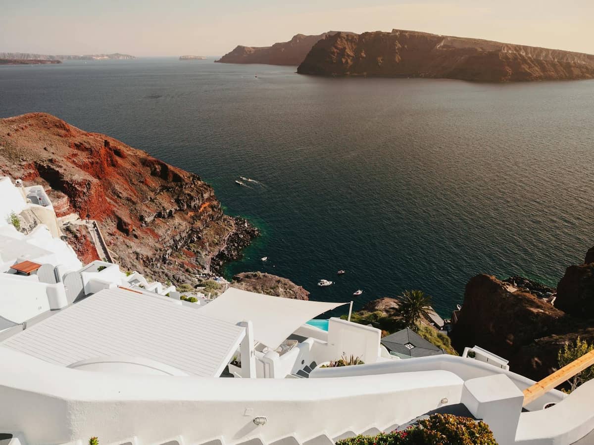 Küstenblick auf Santorini mit dramatischen Klippen, dem tiefblauen Meer und weiß getünchten Gebäuden mit Blick auf das Wasser, die die vielfältige Landschaft der Insel veranschaulichen.
