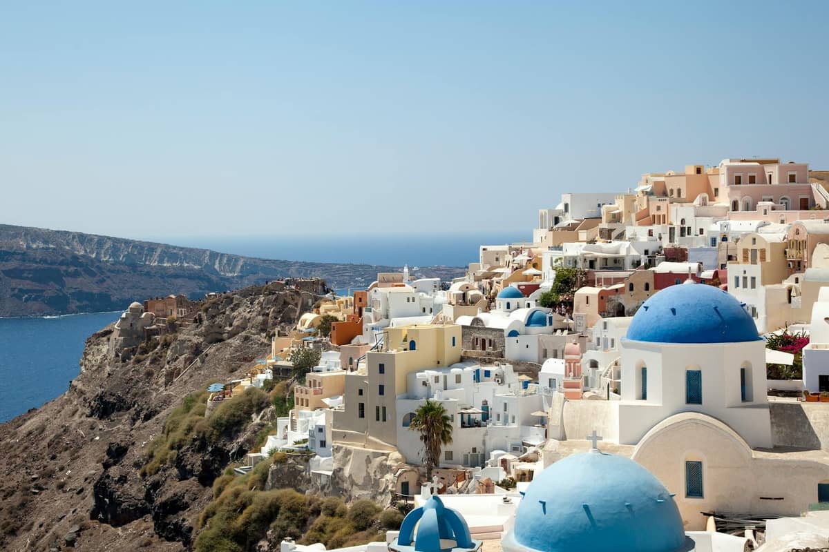 Klassischer Blick auf Santorini mit blaugekuppelten Kirchen, weiß getünchten Gebäuden und beeindruckenden Caldera-Klippen mit Blick auf das tiefblaue Meer.