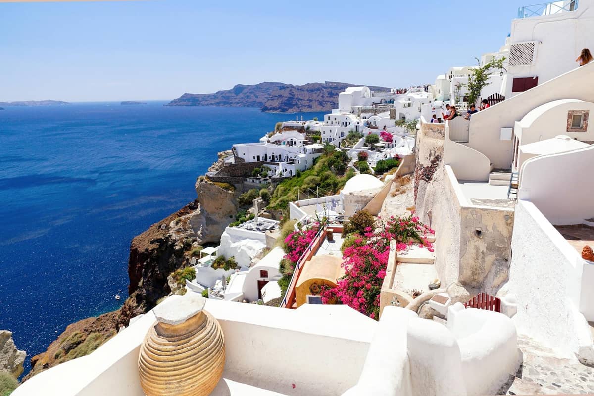 Vista luminosa degli iconici hotel e ville bianchi di Santorini arroccati sulle scogliere con vista sulla caldera e sul mare blu scintillante