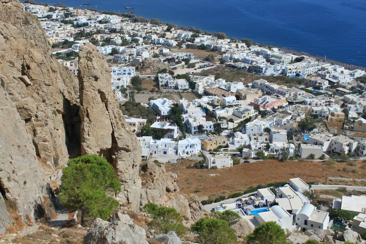 Weitläufige Aussicht auf die Ostküste Santorinis mit vielen weißen Gebäuden und klarem blauem Meer, ein praktisches Gebiet für Familien.