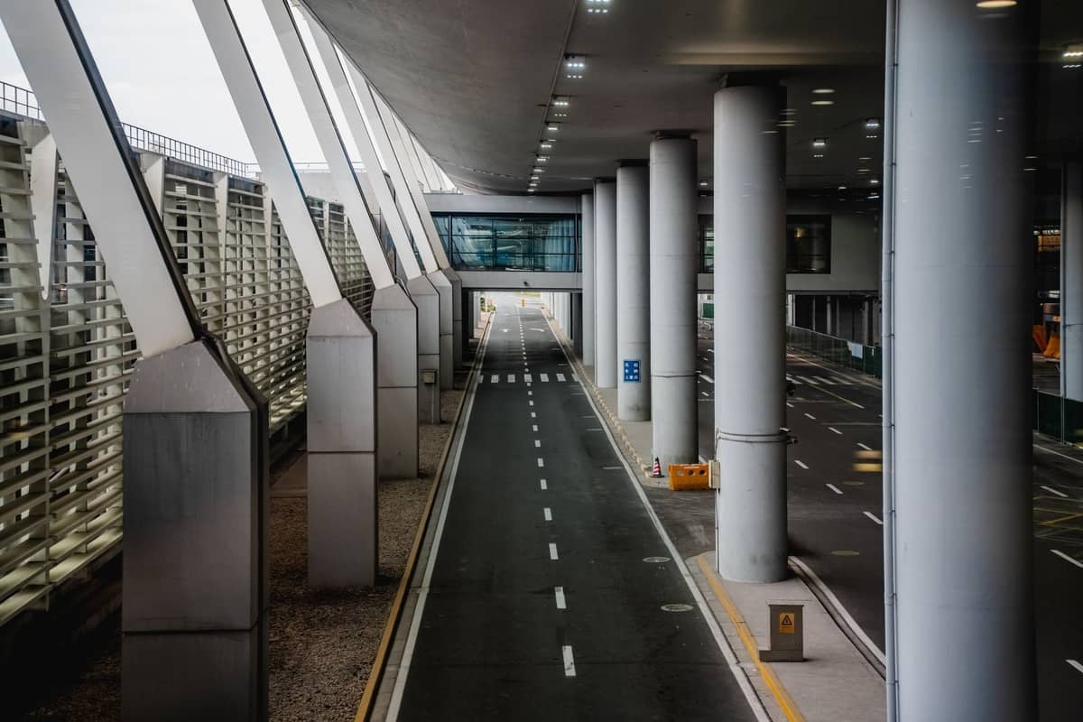 Moderner Ankunftsbereich des Flughafens Francisco Sá Carneiro in Porto mit breiter Fahrbahn, überdachtem Fußweg und Glas-Stahl-Architektur