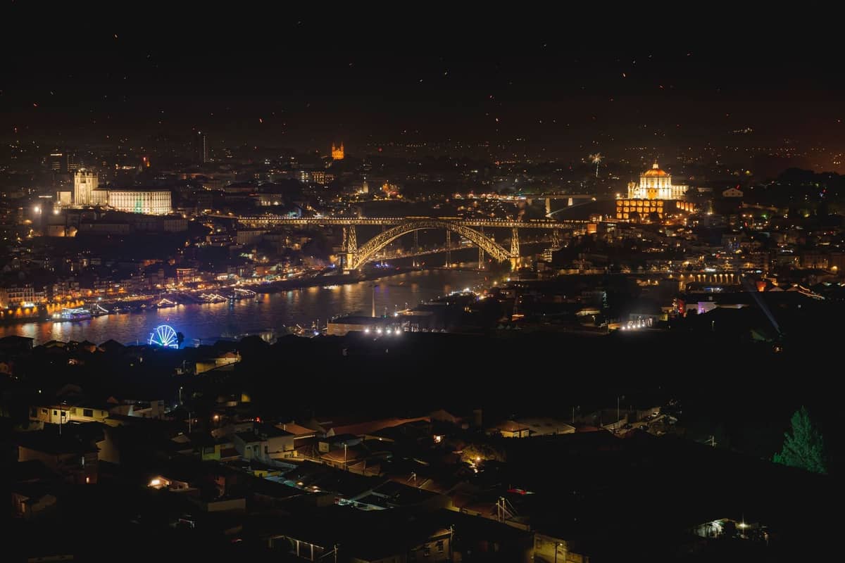 Nächtliche Ansicht von Porto mit der beleuchteten Dom-Luís-I-Brücke über den Fluss Douro und den Stadtlichtern, mit beliebten Festivalorten.