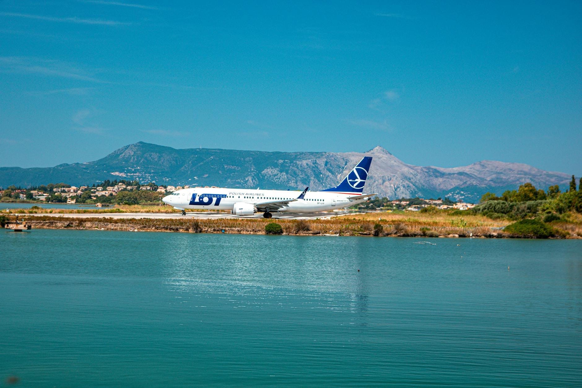 Passagierflugzeug auf der Landebahn des Flughafens Sardinien mit Bergen und Küstenlandschaft im Hintergrund unter blauem Himmel