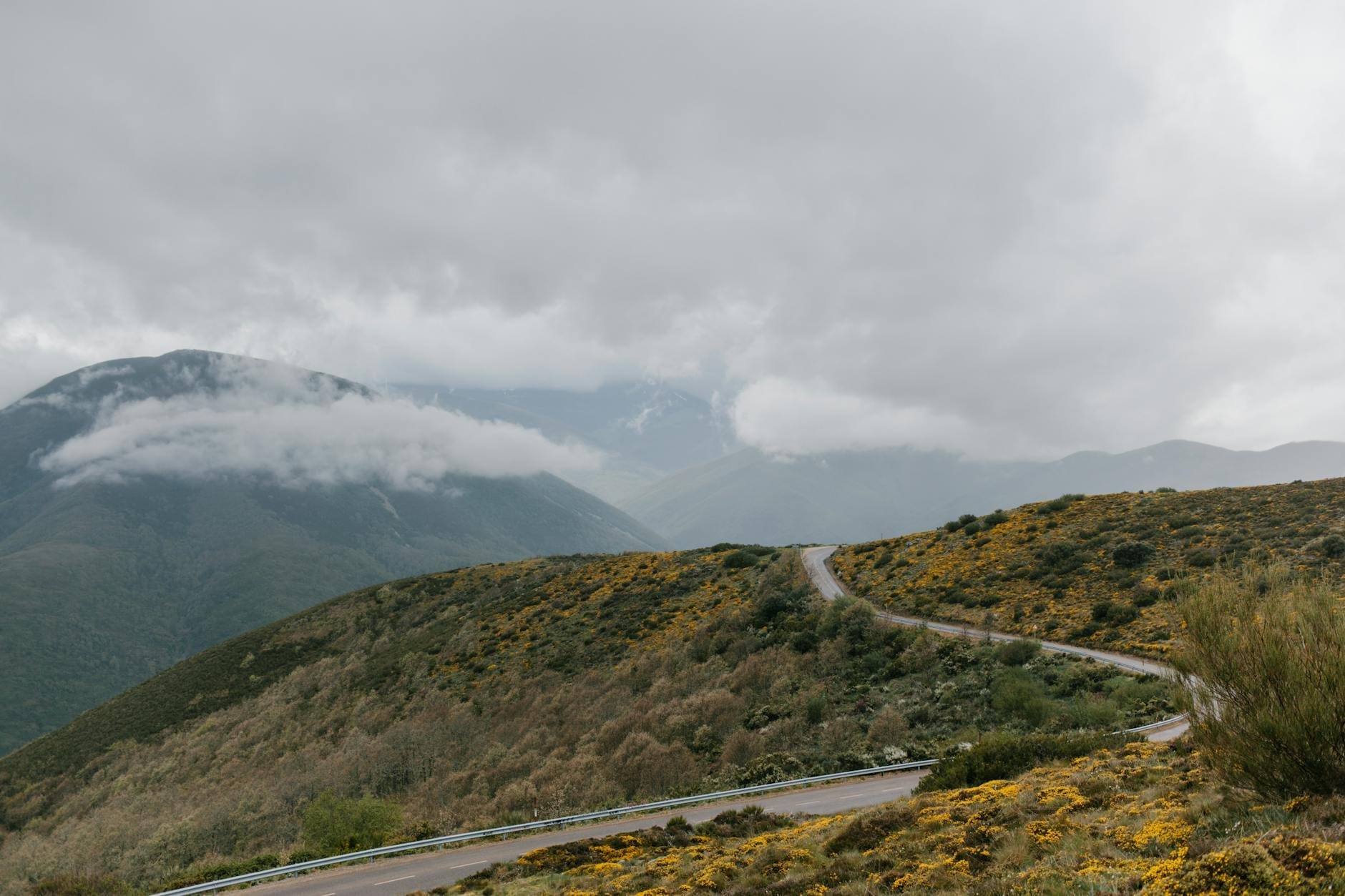 Kurvenreiche Bergstraße auf Sardinien mit dramatischen Hügeln und Wolken, die die Gipfel bedecken, ideal für einen malerischen Roadtrip.
