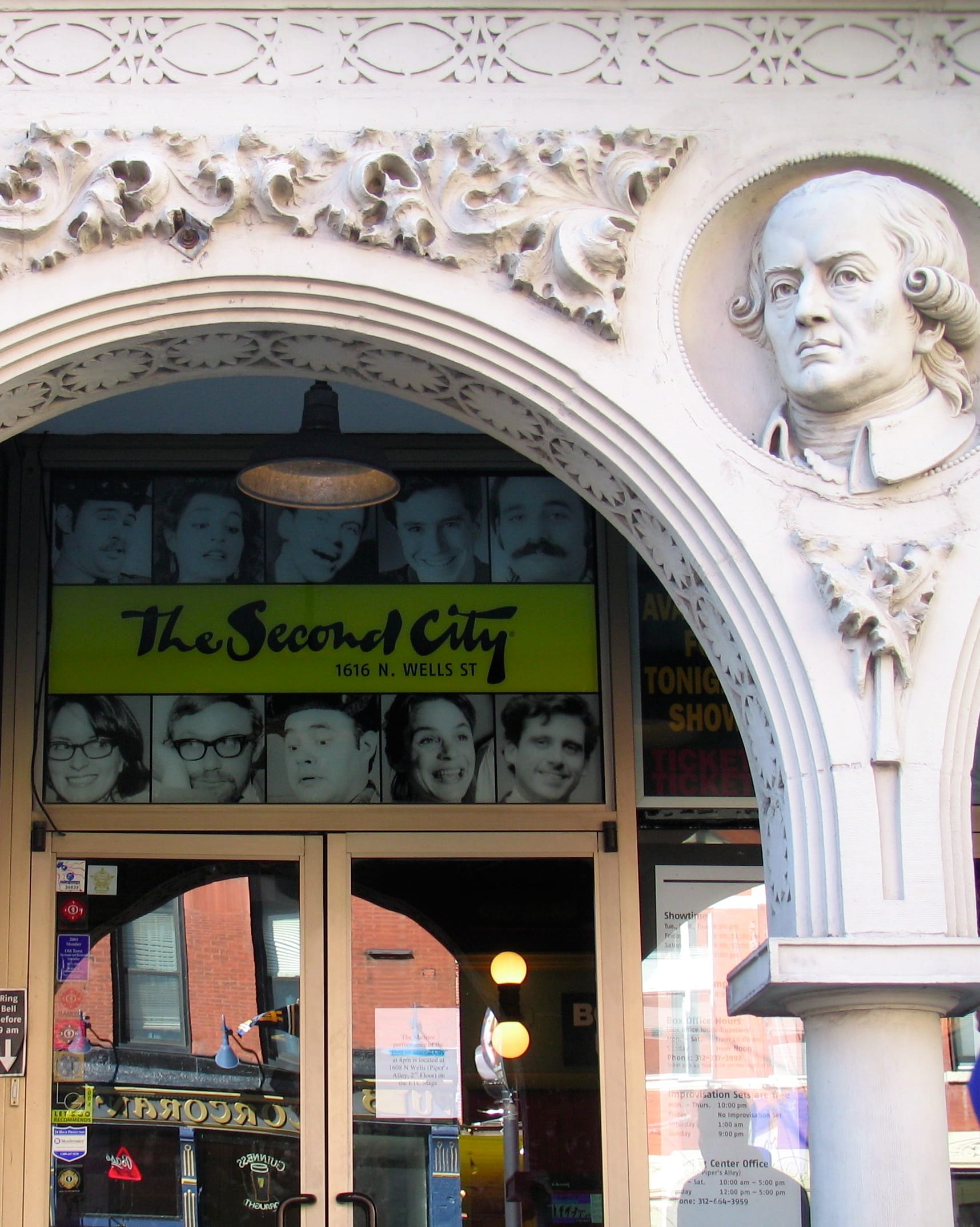 Ingresso del The Second City nel quartiere Old Town di Chicago, con un ornato arco bianco, busto in pietra e ritratti di famosi comici sopra le porte di vetro.