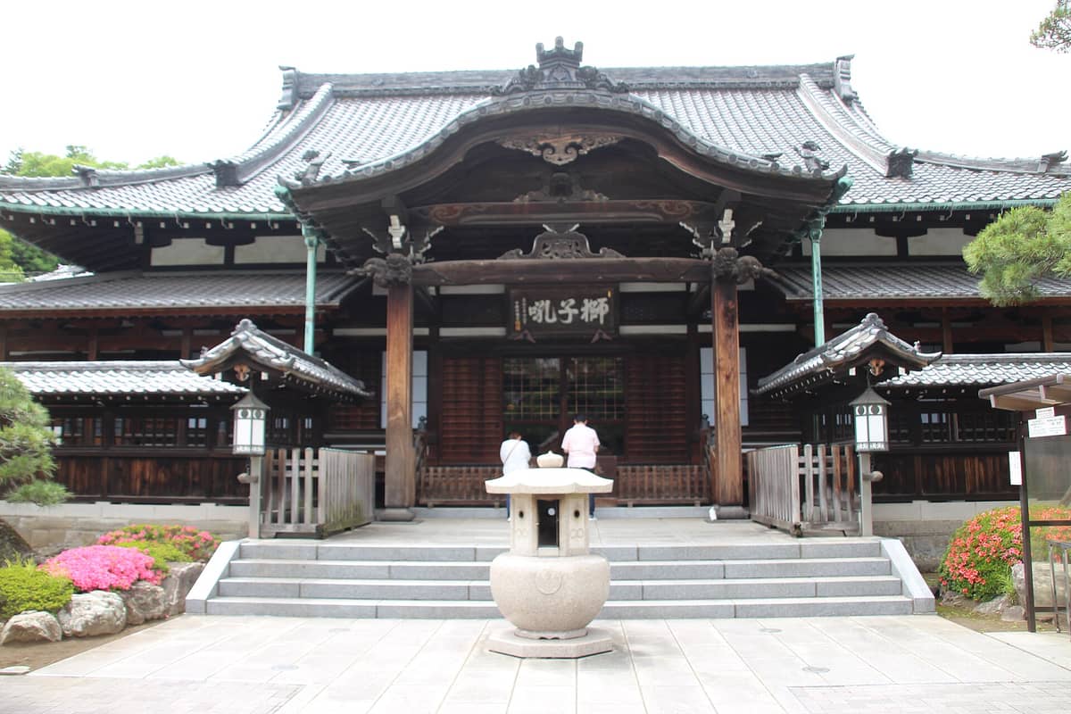 The main hall of Sengaku-ji Temple in Tokyo, featuring traditional wooden architecture and visitors paying their respects at the entrance.