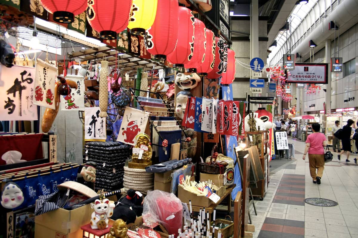 Shops selling kitchenware, lanterns, and restaurant supplies under the covered arcade at Sennichimae Doguyasuji Shopping Street in Osaka.