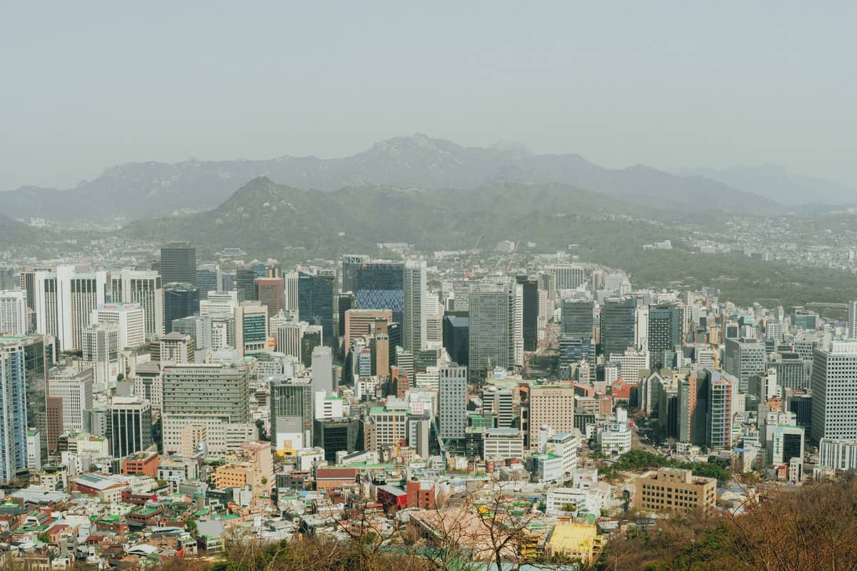 Vista ampla do horizonte de Seul com edifícios da cidade e montanhas ao fundo sob um céu limpo.