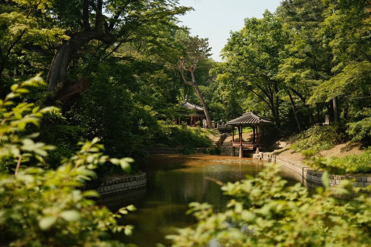 Vista de um lago sereno rodeado de árvores exuberantes e um pavilhão coreano tradicional no Jardim Secreto de Changdeokgung, Seul.