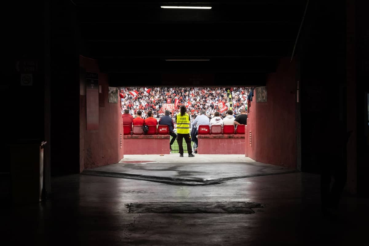 มุมมองจากในอุโมงค์สนามสู่ชั้นอัฒจันทร์ที่แฟนบอล Sevilla FC นั่งเต็ม พร้อมเจ้าหน้าที่รักษาความปลอดภัยเสื้อสะท้อนแสงยืนตรงทางเข้า