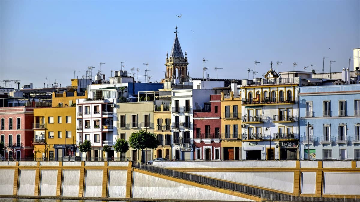 บ้านริมแม่น้ำหลากสีสันและหอคอยโบสถ์ในย่าน Triana ของเมือง Seville มองเห็นจากอีกฝั่งของแม่น้ำ Guadalquivir