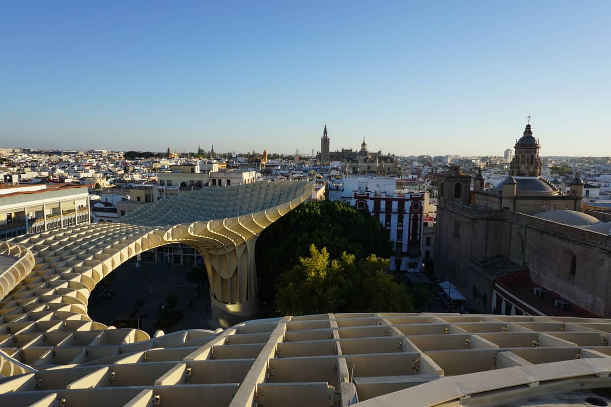 มุมมองแบบไวด์แองเกิลเหนือหลังคาเมืองเซบีญาจากจุดสูง โดดเด่นด้วย Metropol Parasol และเส้นขอบฟ้าของเมืองรวมถึงหอคอย Giralda