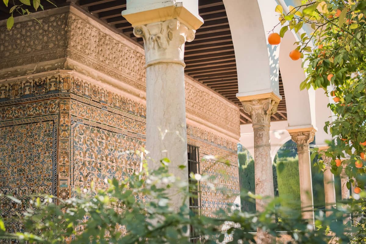 ลานกลางบ้านในเมือง Seville พร้อมต้นส้มที่กำลังออกผลและสถาปัตยกรรมมัวร์ที่วิจิตรงดงามในพื้นหลัง สะท้อนบรรยากาศท้องถิ่นและฤดูกาลของผลไม้