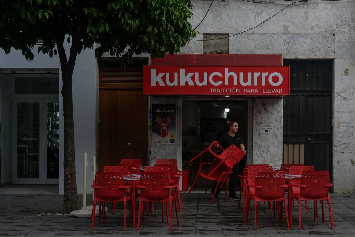 บริเวณที่นั่งกลางแจ้งของร้านอาหารลำลองชื่อ Kukuchurro พร้อมเก้าอี้และโต๊ะสีแดงจำนวนมากบนทางเท้าในเมือง Seville