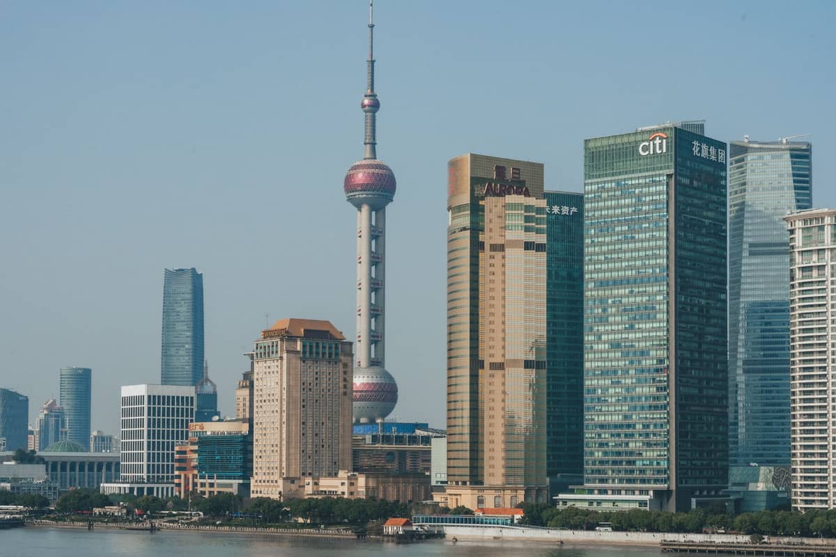 Weitläufige Tagesansicht der ikonischen Skyline Shanghais mit dem Oriental Pearl Tower, den modernen Wolkenkratzern von Lujiazui und dem historischen Bund-Uferbereich im Vordergrund.