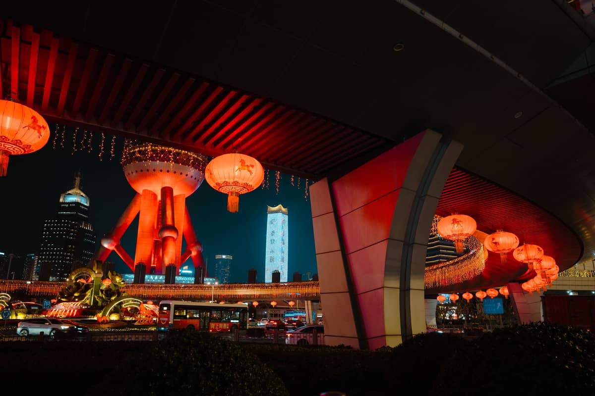 Rote chinesische Laternen schmücken den erhöhten Fußweg unterhalb des Oriental Pearl Tower in Shanghai bei Nacht während der Frühlingsfest-Feierlichkeiten.