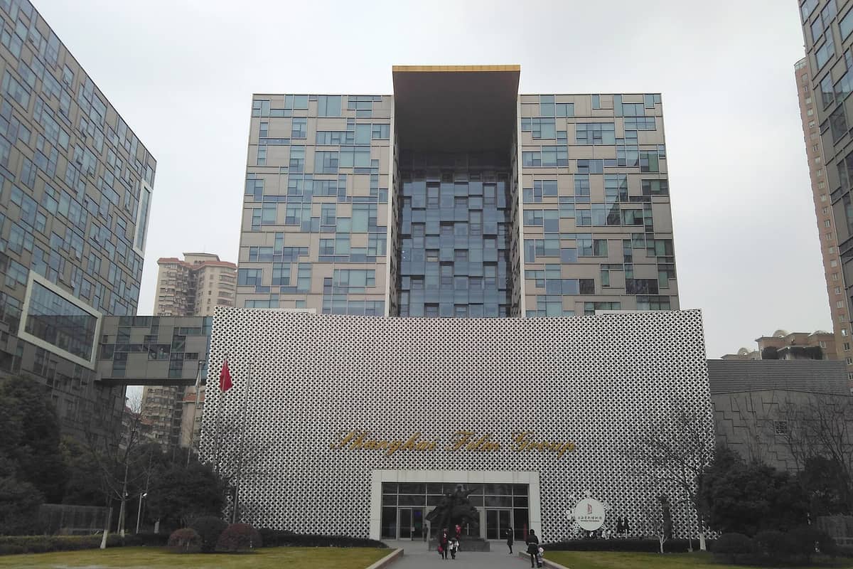 Moderne Fassade des Shanghai Film Museums mit gemusterter Wand, goldenem Schriftzug und modernen Glasgebäuden rund um den Eingang.