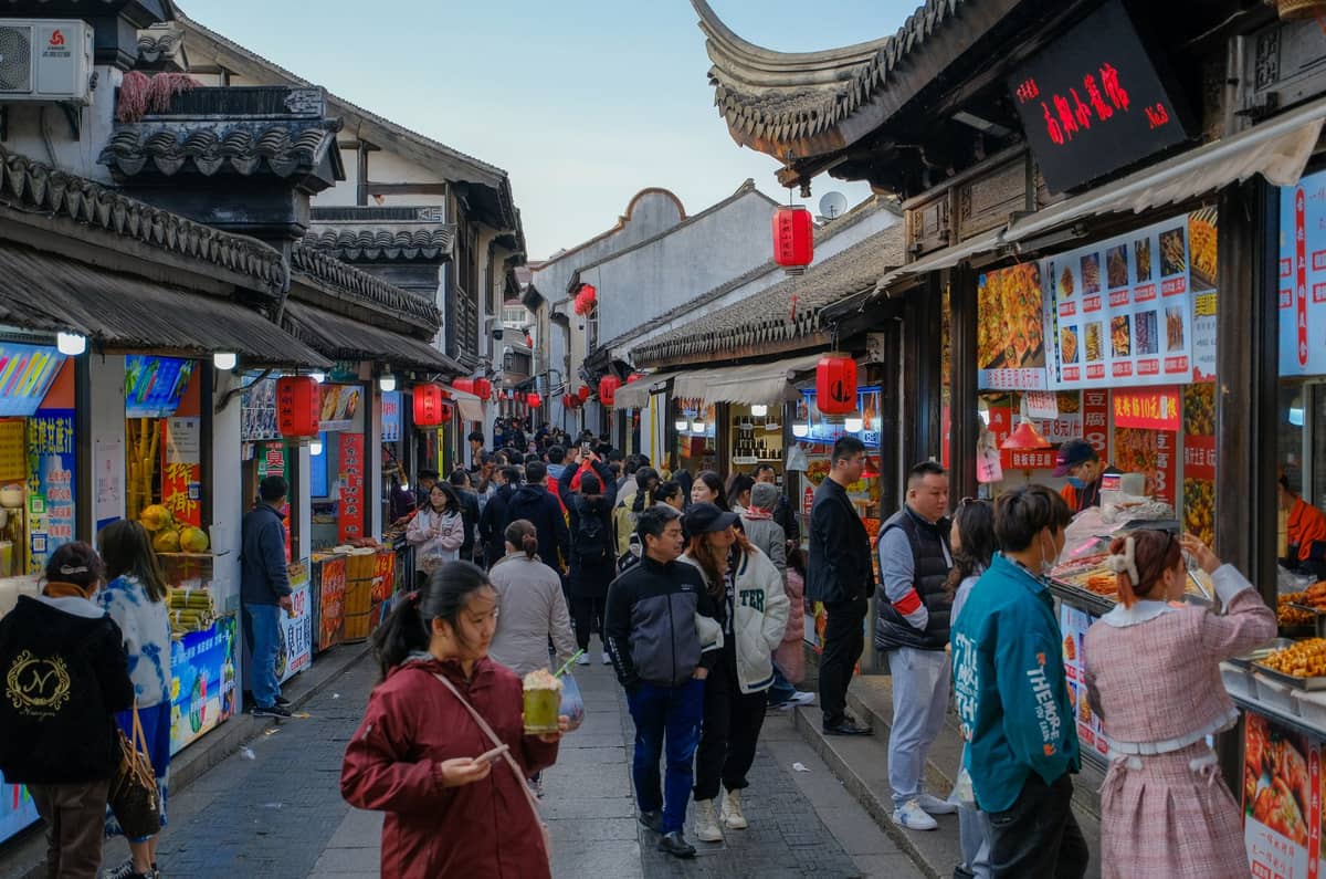 Marché de rue animé à Shanghai avec des stands de nourriture, des lanternes rouges et des foules de gens qui font leurs courses et mangent