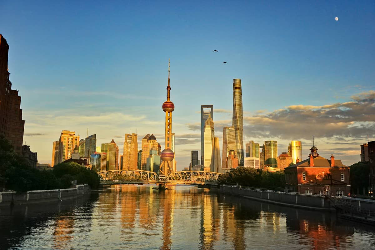 Pemandangan panoramik cakrawala Shanghai dan sungai saat matahari terbenam, dengan langit cerah dan awan dalam cahaya musim gugur yang semarak.