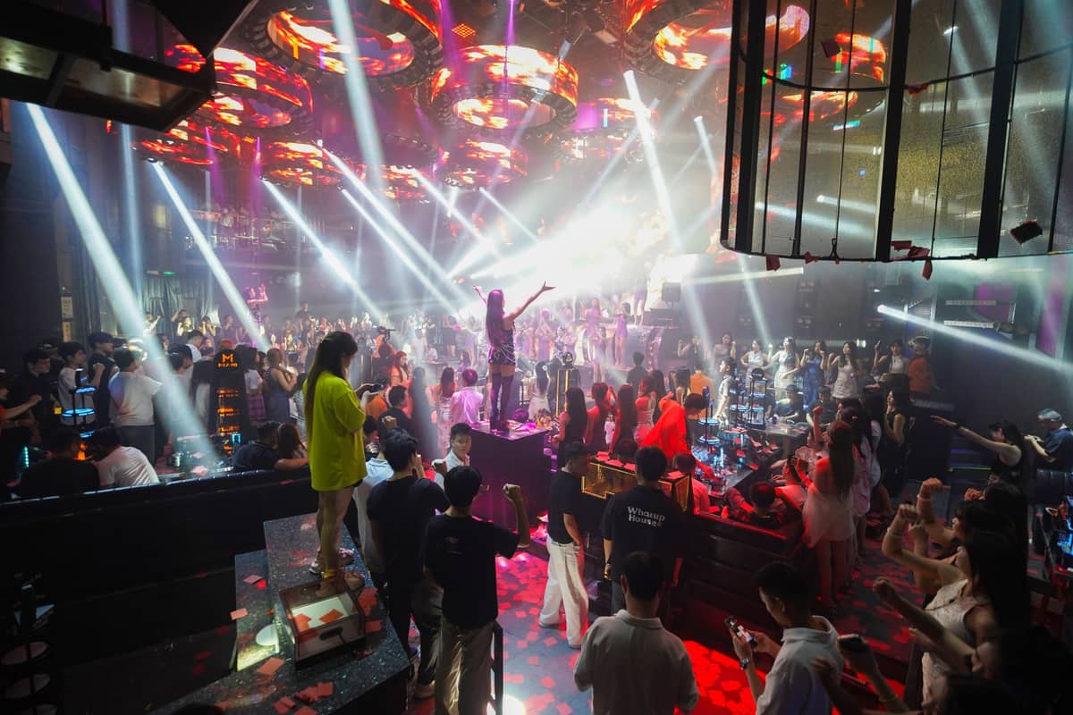 Grande boîte de nuit bondée avec des personnes qui dansent et des éclairages de scène, capturant une scène de club vibrante à Shanghai.