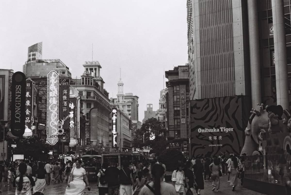 Crowded shopping street in Shanghai with many pedestrians and large neon signs, evoking a busy area known for pickpocketing risks.