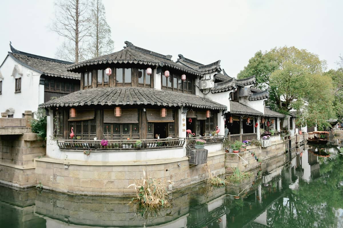 Traditional water town buildings with tiled roofs and lanterns on a quiet canal, reflecting Tongli’s historic architecture and serene atmosphere.