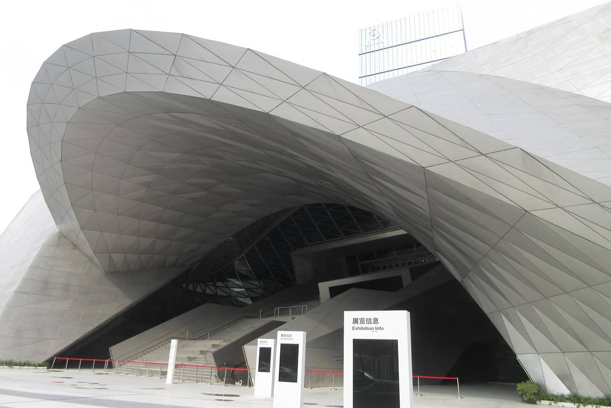 Entrada futurista de metal e vidro do museu MOCAPE em Shenzhen, destacando suas ousadas curvas arquitetônicas e fachada geométrica.