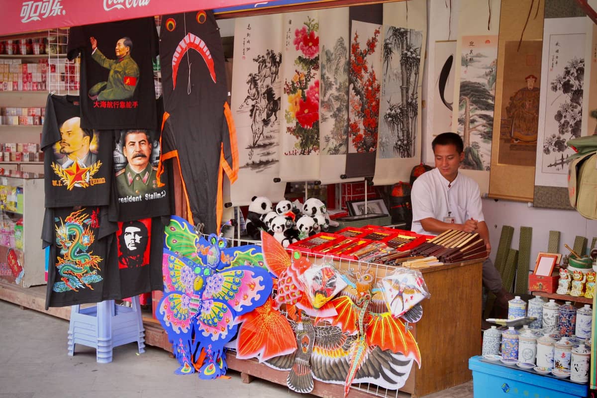 Ein Marktstand in Beijing mit bunten Drachen, chinesischen Kalligraphie-Rollen, Panda-Spielzeug und traditionellem Kunsthandwerk zum Verkauf.