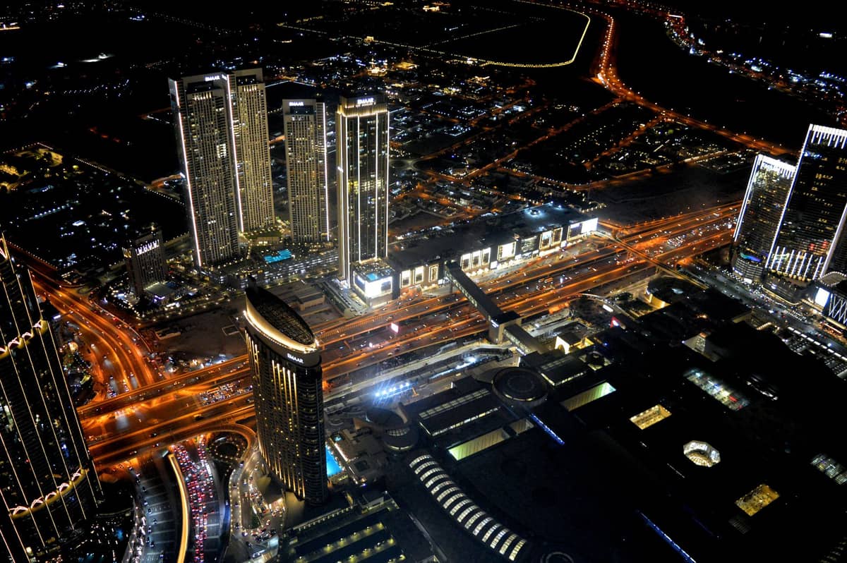 Nächtliche Luftaufnahme der Dubai Mall und Downtown Dubai, mit dem Metro-Übergang und den Stadtlichtern gut sichtbar.