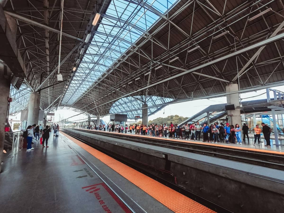 Moderne, geräumige U-Bahn-Station mit Glasdach, wartenden Personen auf dem Bahnsteig und hellem, natürlichem Tageslicht, typisch für den öffentlichen Nahverkehr von Guadalajara.