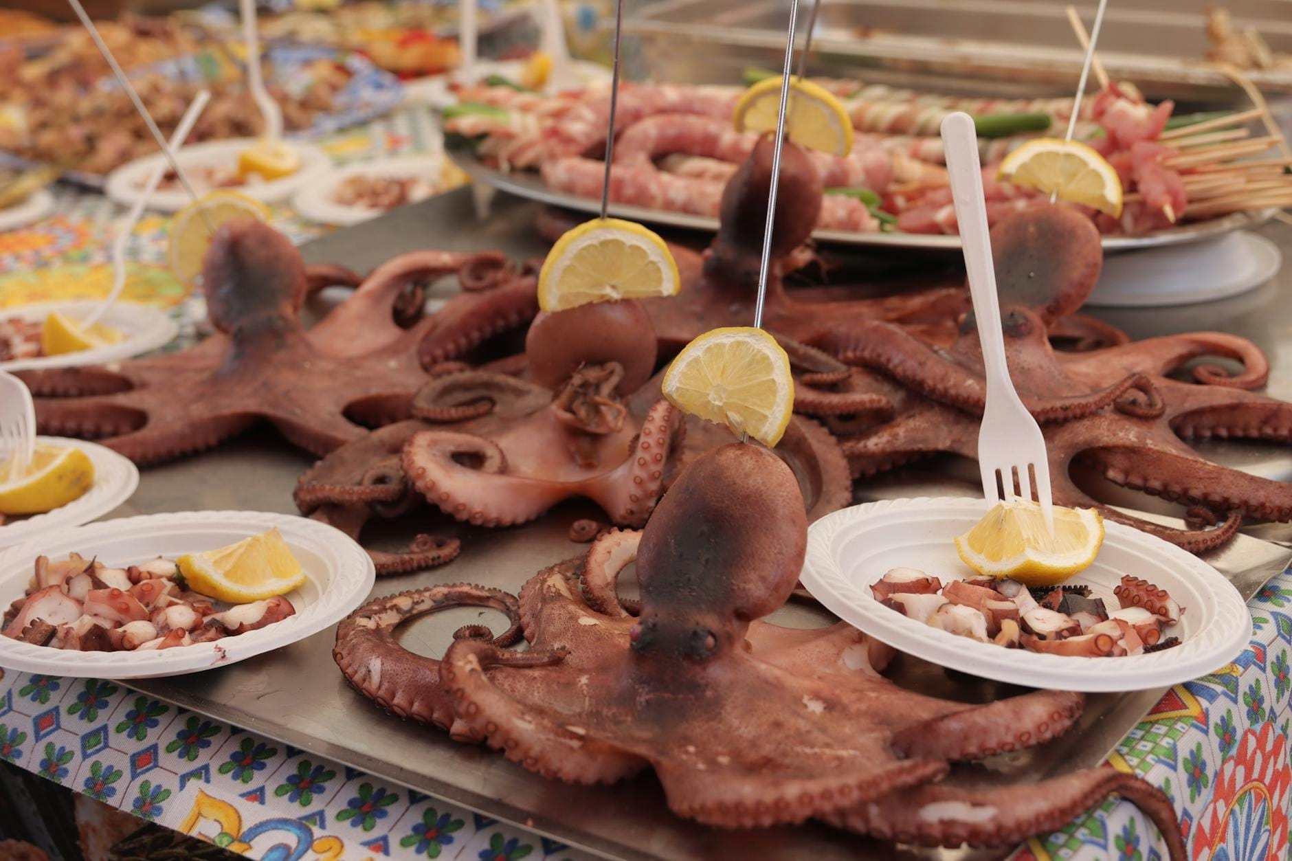 Frisch zubereiteter ganzer Oktopus mit Zitronenspalten an einem Straßenimbissstand in Sizilien.