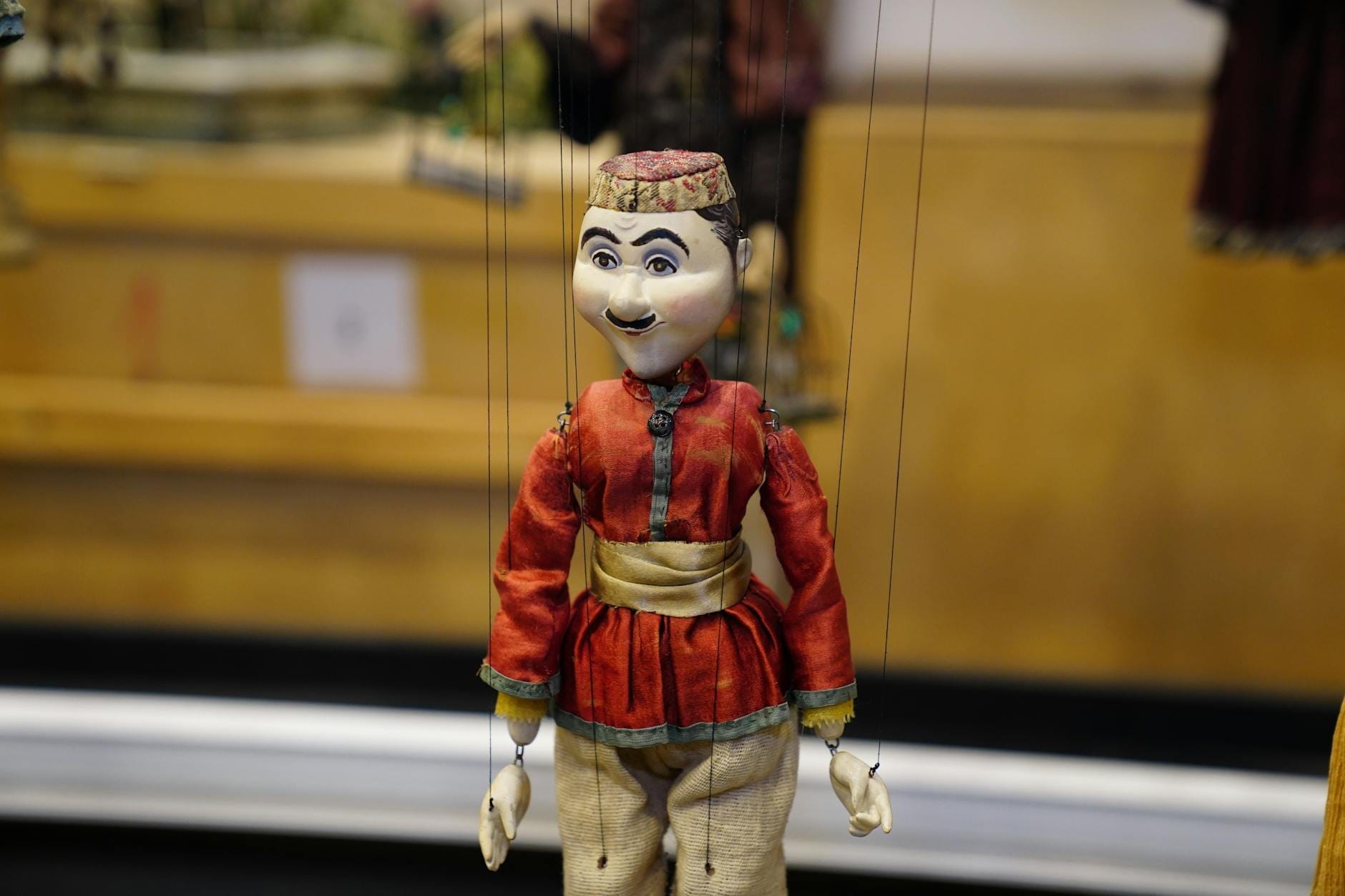 Eine traditionelle Marionette in aufwändigem Kostüm, an Fäden aufgehängt, vor einer Theaterkulisse, typisch für das mediterrane oder sizilianische Marionettentheater.