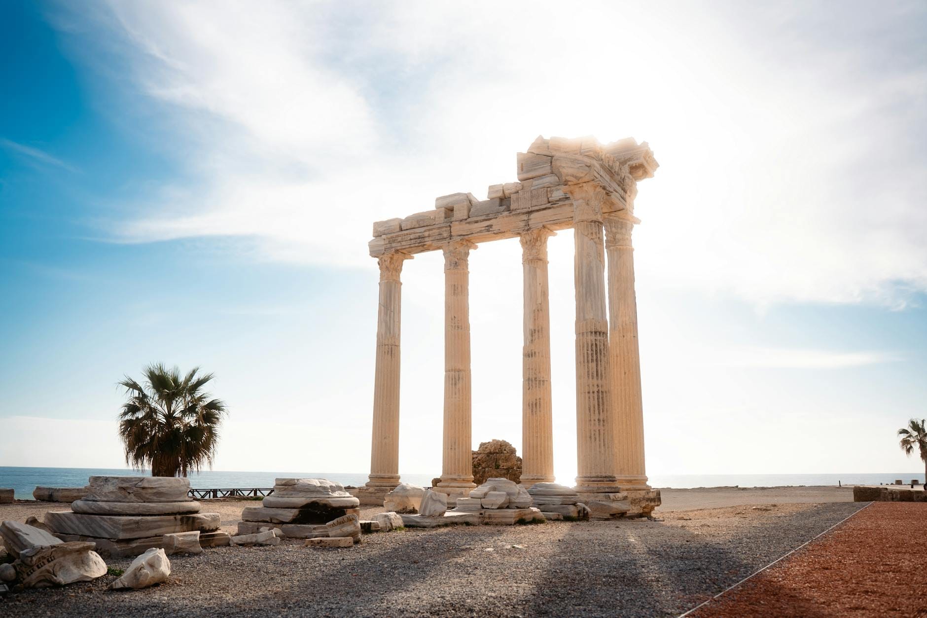 Le cinque colonne del Tempio di Apollo si ergono sul lungomare con una luce drammatica e palme lungo la costa mediterranea a Side, in Turchia.