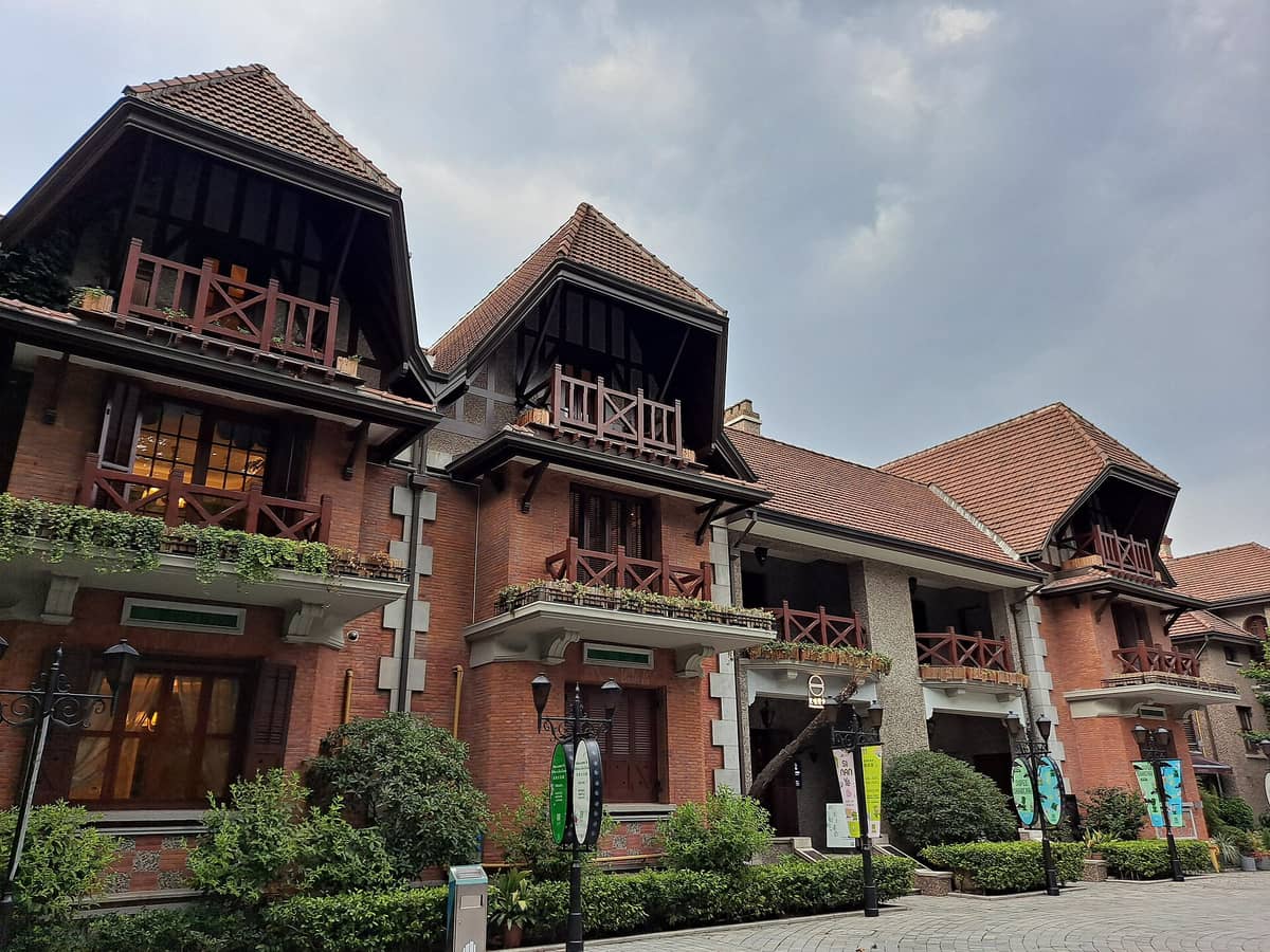 Eine Reihe gut erhaltener Villen aus dem frühen 20. Jahrhundert mit roten Ziegeldächern und verzierten Balkonen, umgeben von Grün, im Shanghais Viertel Sinan Mansions.
