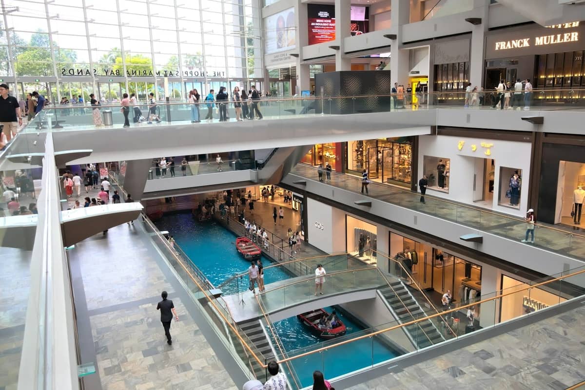 Interior of The Shoppes at Marina Bay Sands with luxury boutiques and indoor canal with gondola, viewed from above.