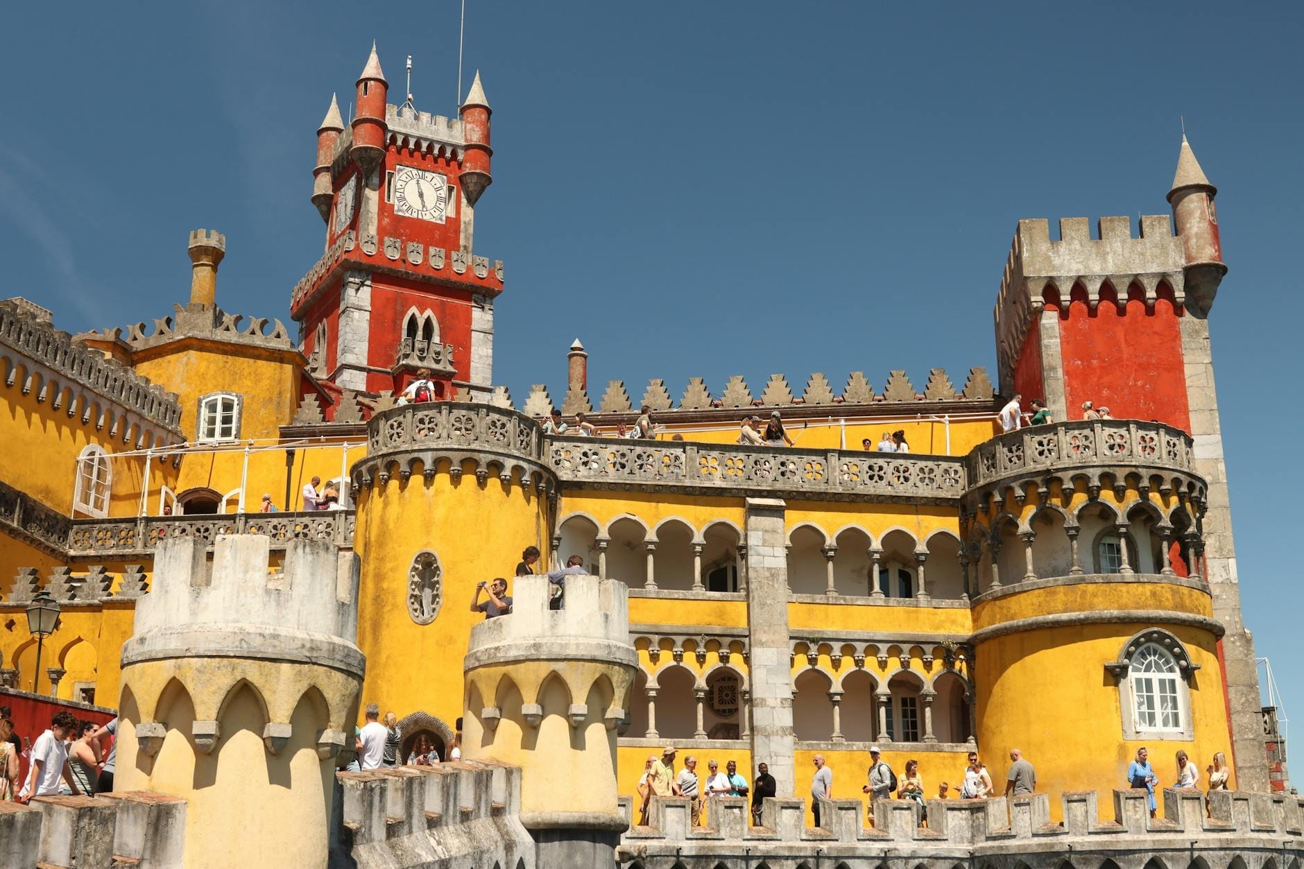 Des foules de touristes rassemblées devant le coloré et emblématique Palais da Pena à Sintra par une belle journée d'été.
