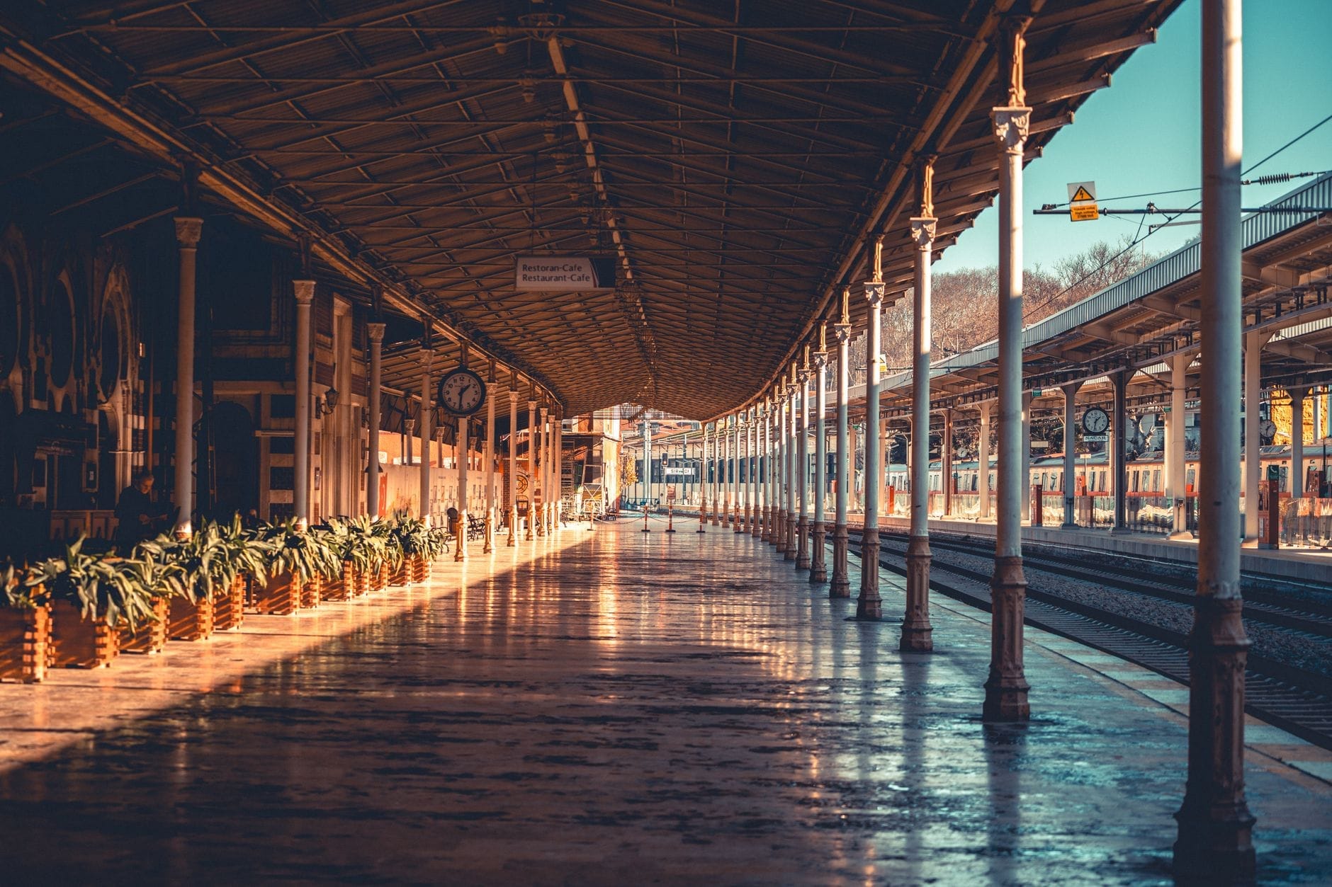 Il binario della stazione di Sirkeci inondato di luce solare, con colonne ornate, un orologio d'epoca e i binari che si perdono in lontananza, evocando l'atmosfera storica del leggendario capolinea ferroviario.