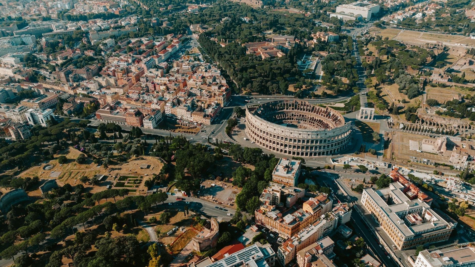Aerial view of the Colosseum and surrounding historic center of Rome on a sunny day.