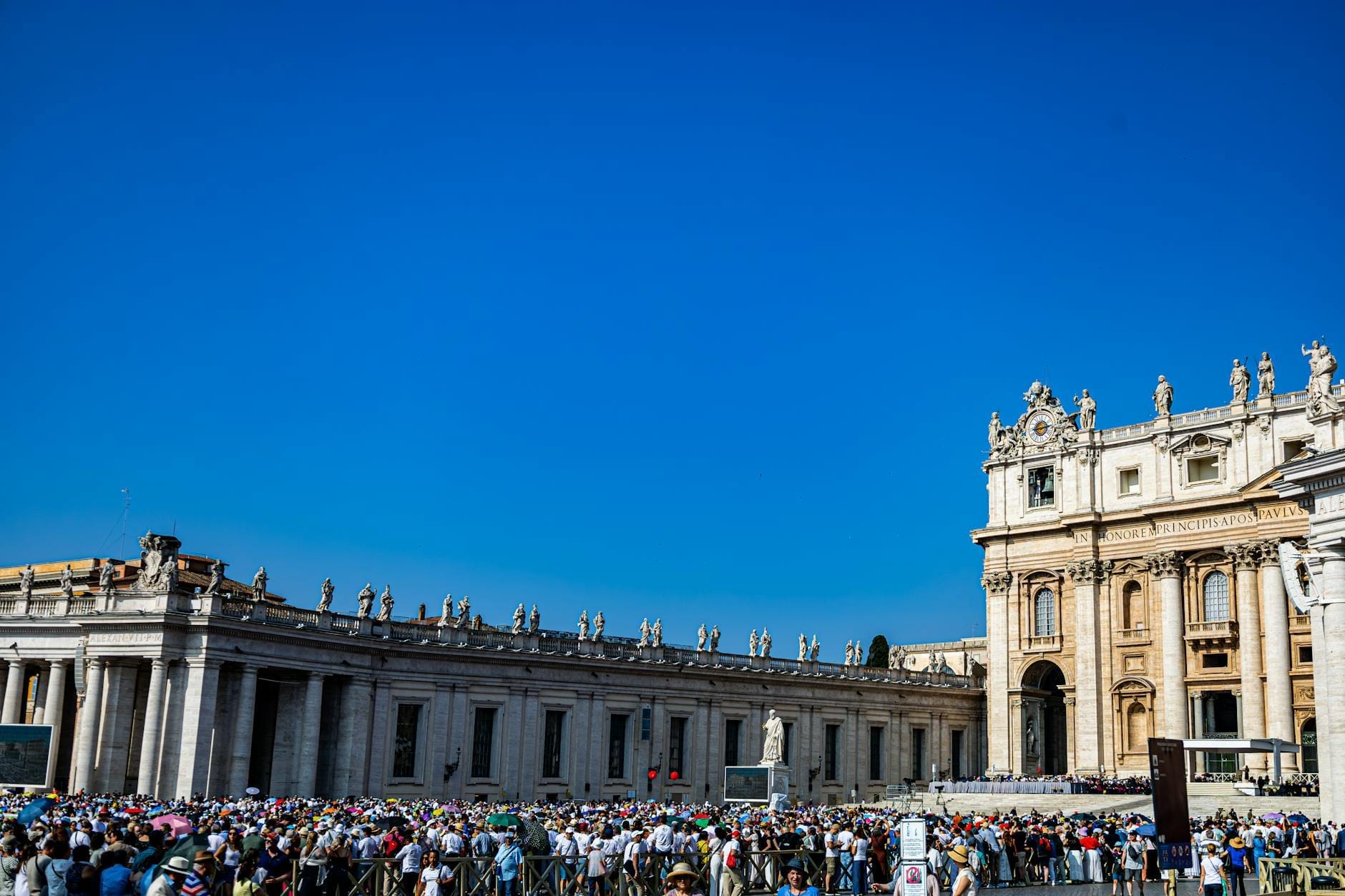 Large crowd of tourists queuing outside St. Peter’s Basilica under a bright blue sky in Vatican City, Rome.