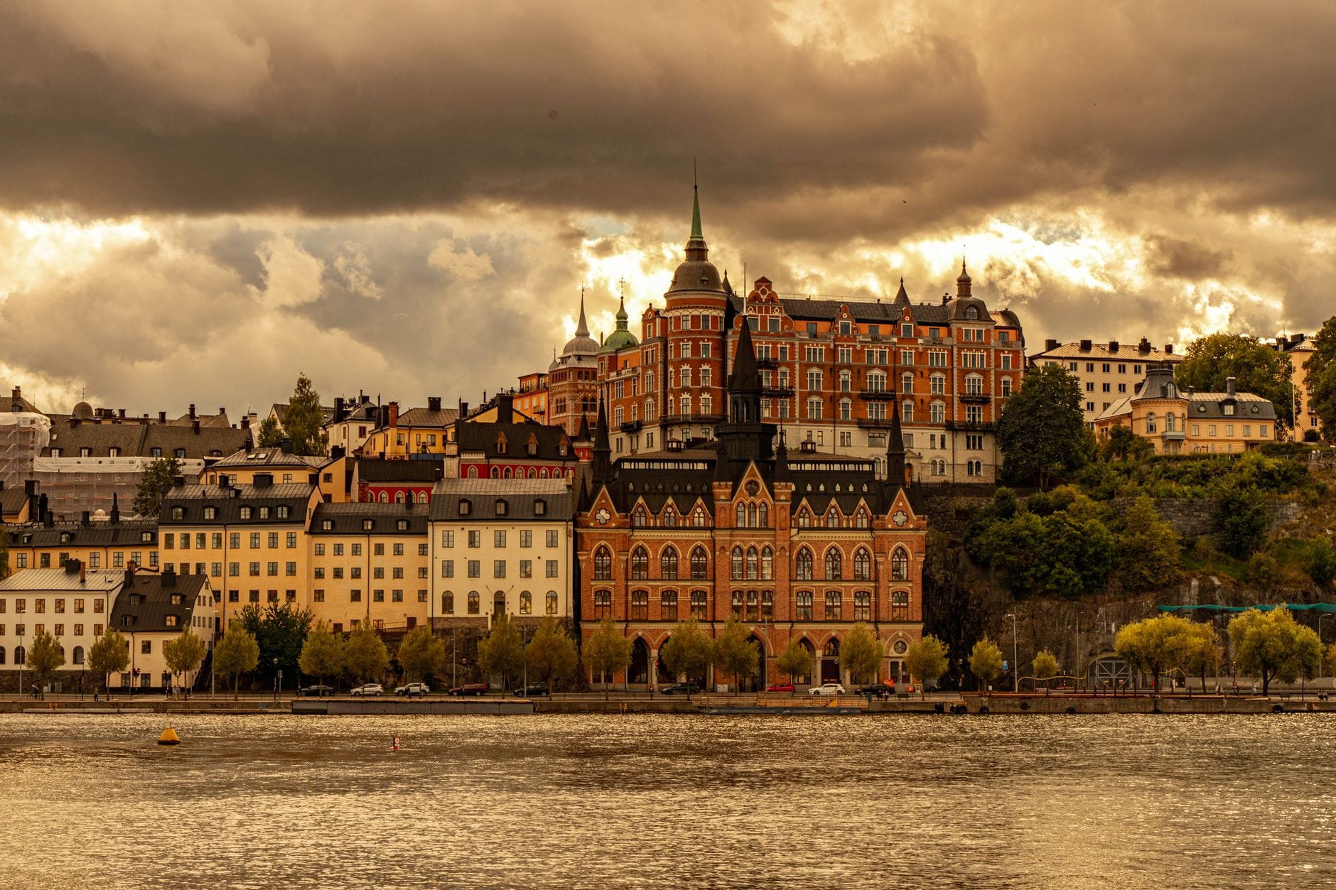 วิวหน้าผา Mariaberget อันโดดเด่นของ Södermalm พร้อมตึกอิฐประวัติศาสตร์และอพาร์ตเมนต์สีสันสดใสริมริมน้ำใต้ท้องฟ้าครึ้ม