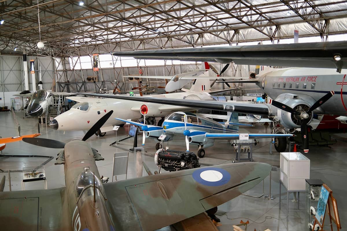 Wiele historycznych samolotów wystawionych wewnątrz hangaru South Australian Aviation Museum, w tym samoloty śmigłowe i odrzutowe pod przemysłowym metalowym dachem.