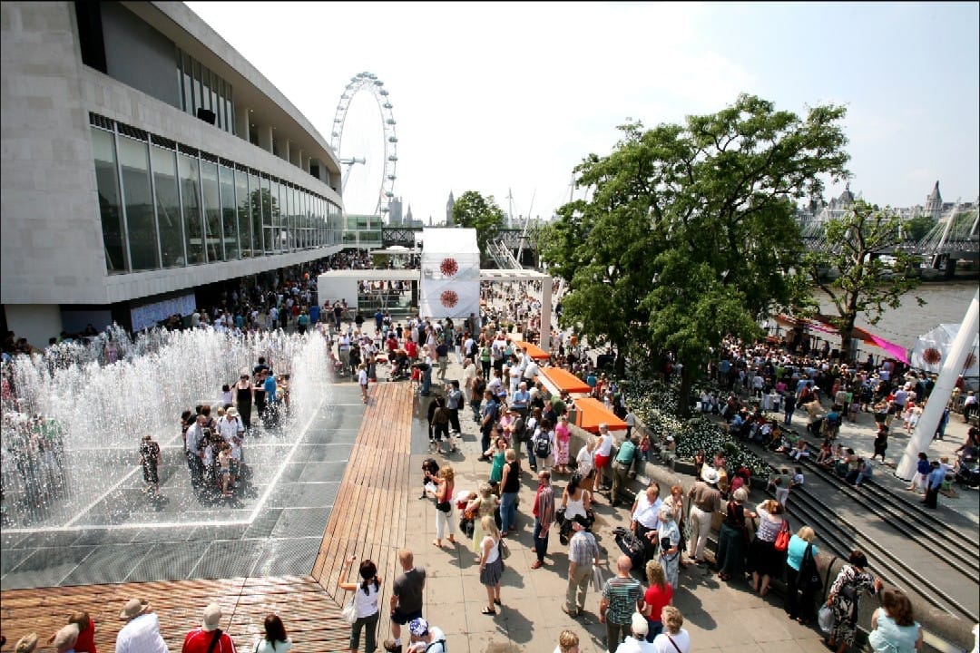 Le folle si radunano attorno alle fontane fuori dal Southbank Centre in una giornata di sole, con il London Eye e il Tamigi visibili sullo sfondo.