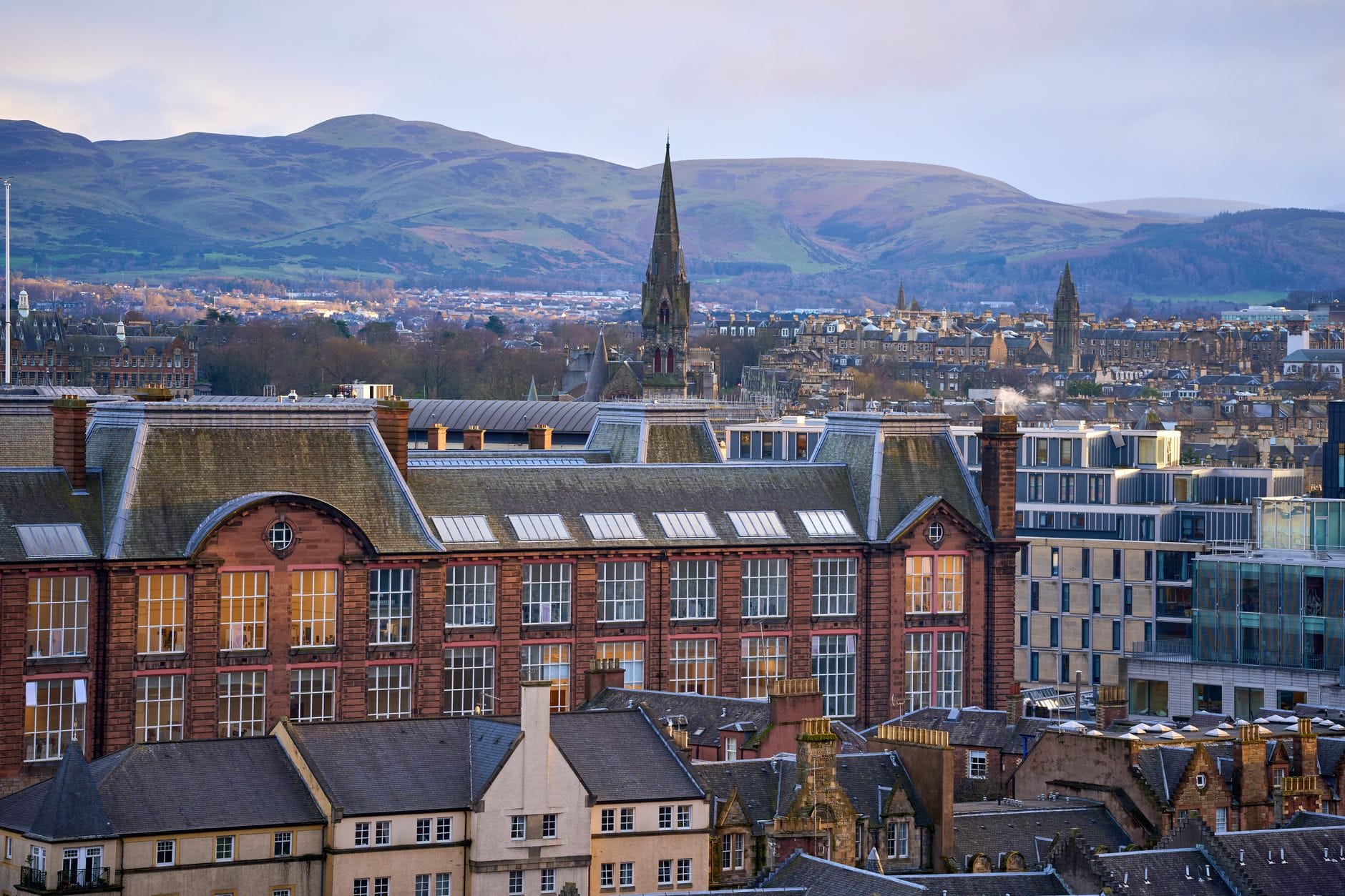 Blick über Southside in Richtung Newington mit dem historischen Gebäude der ehemaligen James Clark School, dem Turm von St. Peters, Miethäusern und den Hügeln des Arthur's Seat im Hintergrund.