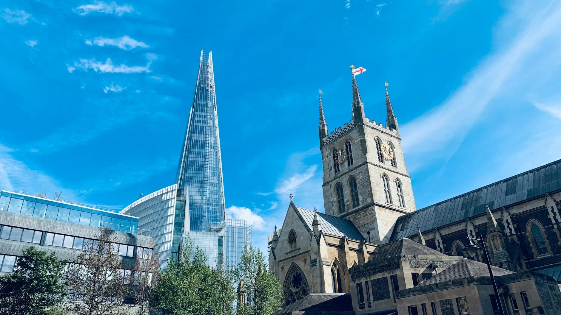 Vista della Cattedrale di Southwark con la sua torre gotica e il grattacielo The Shard sullo sfondo, sotto un cielo azzurro e luminoso a Londra.