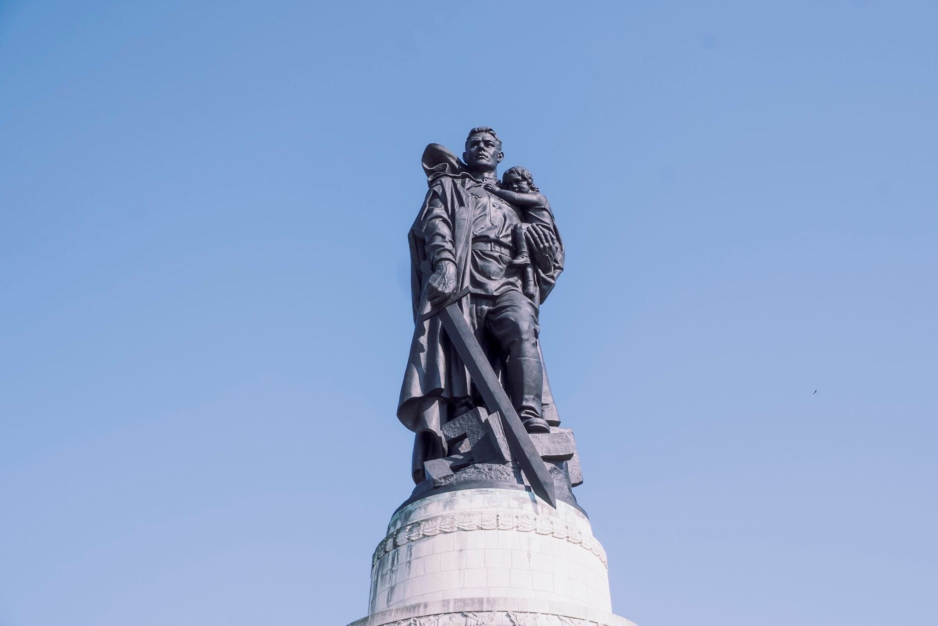 L'iconica statua in bronzo del soldato sovietico alta 12 metri, in cima a un tumulo al Memoriale Sovietico nel Treptower Park di Berlino, fotografata contro un cielo azzurro limpido.
